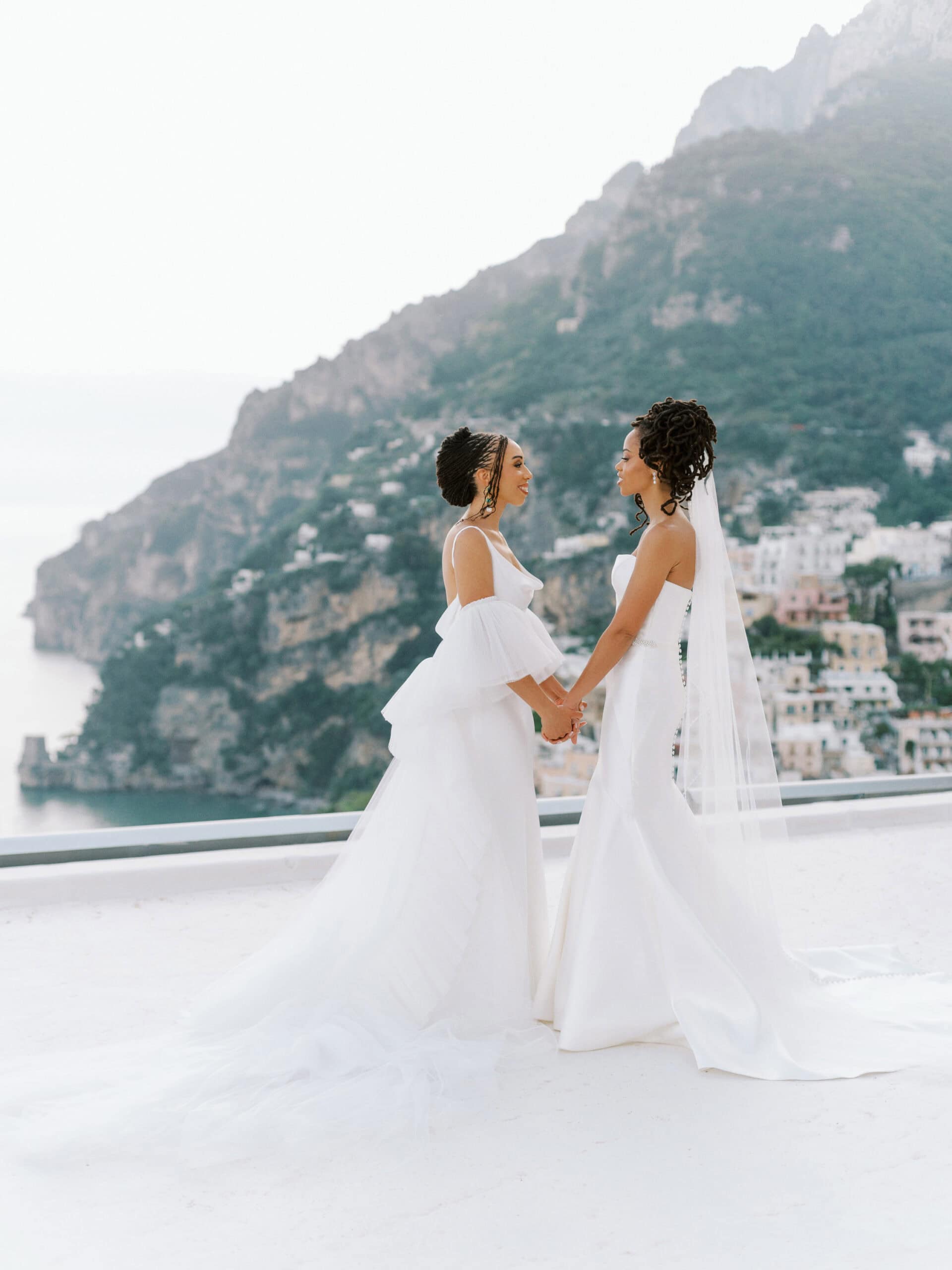 Emotional brides holding hands overlooking the Amalfi Coast